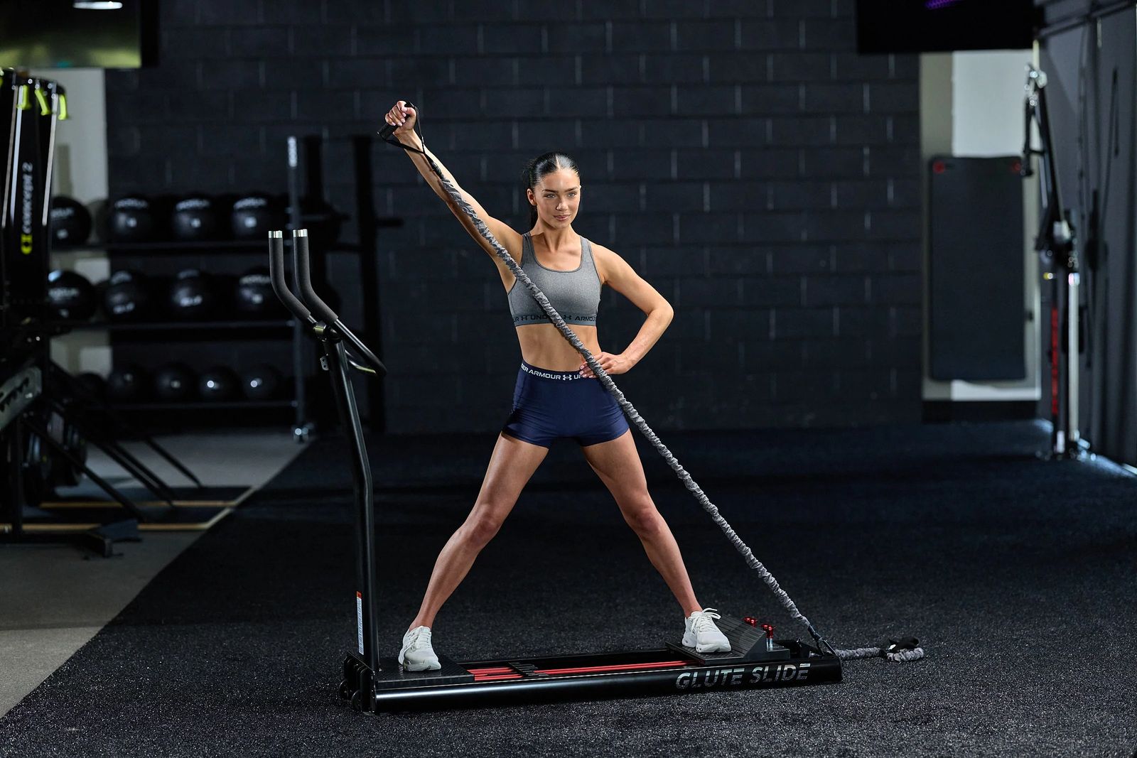 Woman doing a standing cable reach on the Glute Slide in a gym